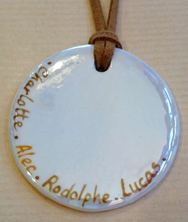 Pendentif rond personnalisé par les prénoms des petits enfants dans différents tons de beige.